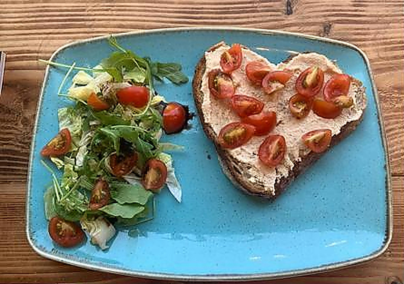 Tomato toast with a fresh side salad on a blue plate
