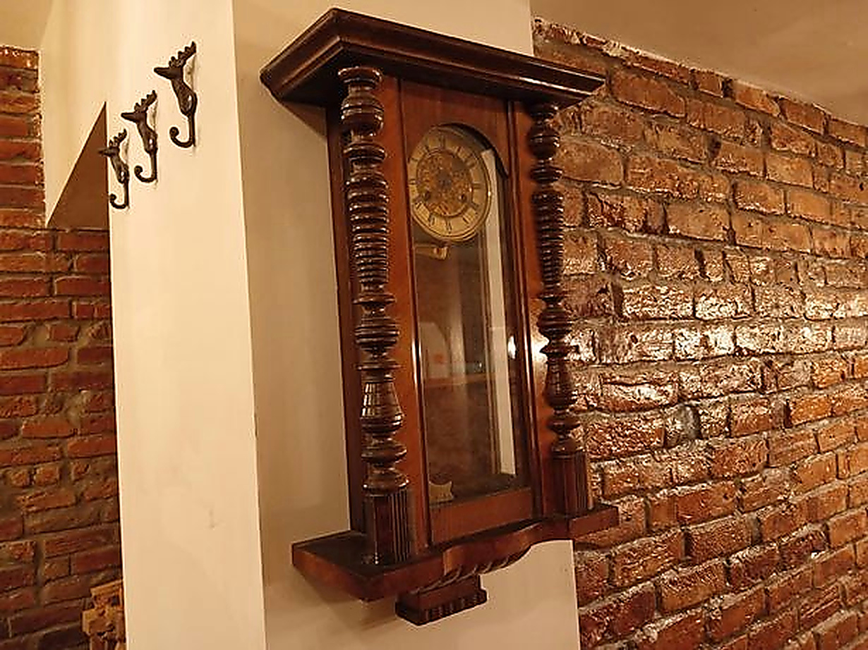 A vintage wooden clock against the café's exposed brick wall