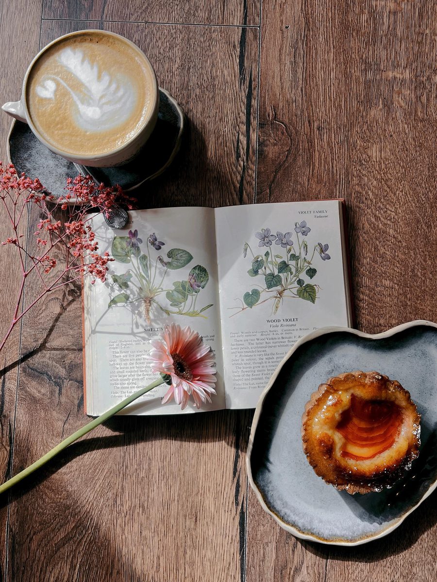 A plum tartlet with a latte on the wooden table