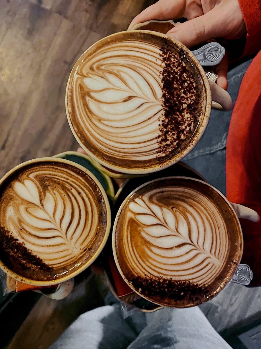 Two cups with leaf latte art on the wooden counter