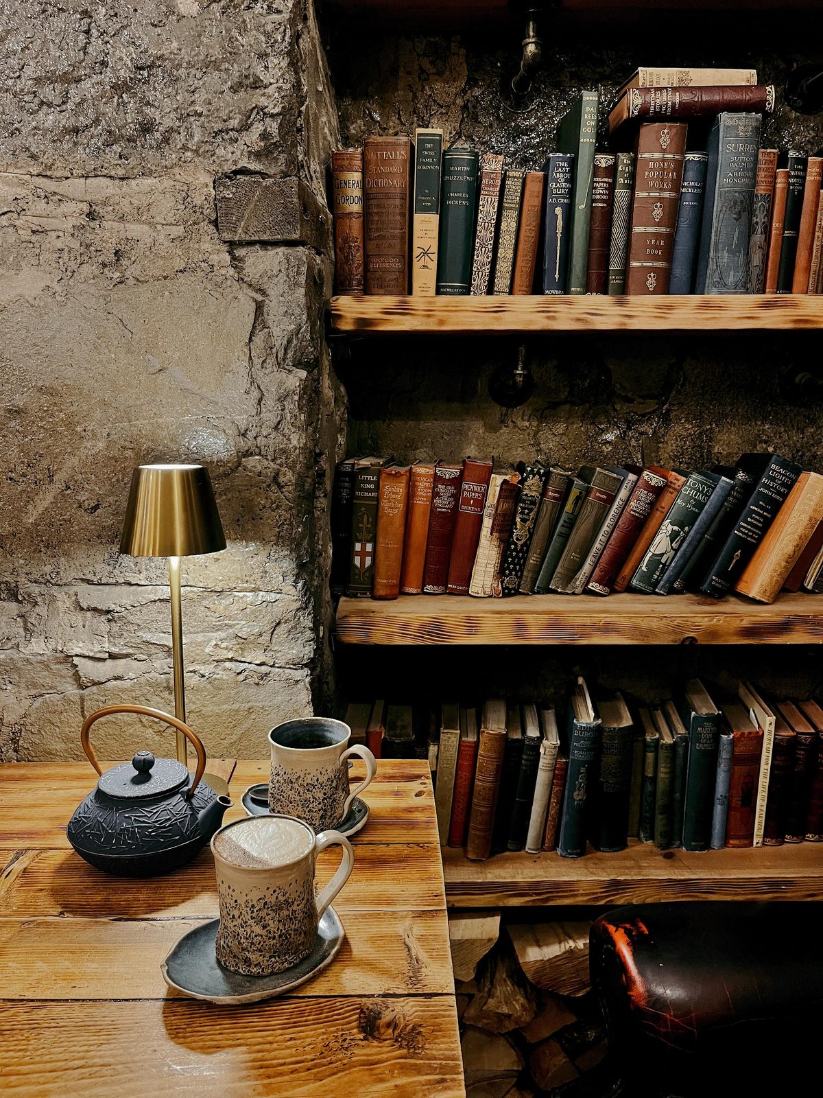 The bookshelf corner — vintage paperbacks, a teapot and lamplight